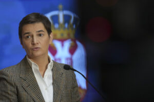 Ana Brnabic står i kavaj och uppknäppt skjorta med det Serbiska statsvapnet i bakgrunden. Bilden kommer från 2024 under ett tal hon höll i Serbiens parlament.