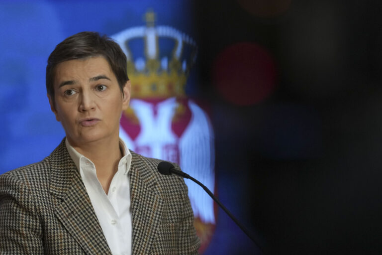 Ana Brnabic står i kavaj och uppknäppt skjorta med det Serbiska statsvapnet i bakgrunden. Bilden kommer från 2024 under ett tal hon höll i Serbiens parlament.