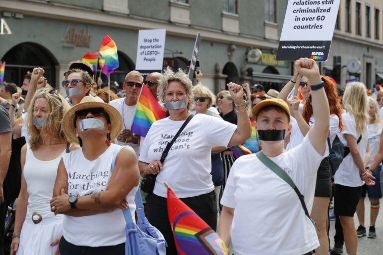 Bild från Stockholm Pride och avdelningen Marching for thoose who can't. Bilder på personer med munnarna tejpade, plakat där det syns "Stop the deportation of LGBTQI-people och ...relations still criminalized in over 60 countries.